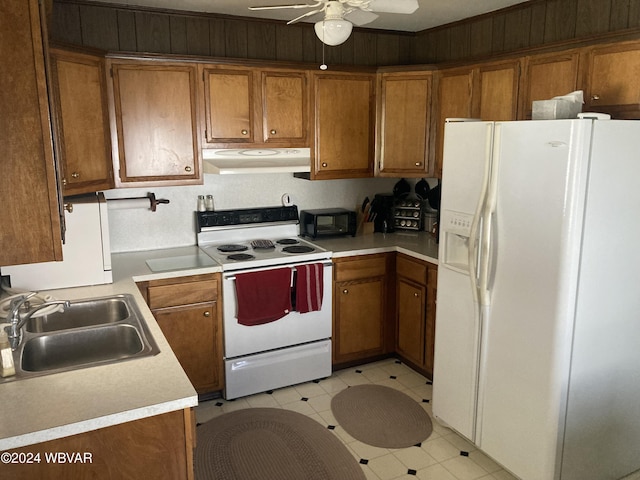 kitchen featuring brown cabinetry, white appliances, a sink, and under cabinet range hood