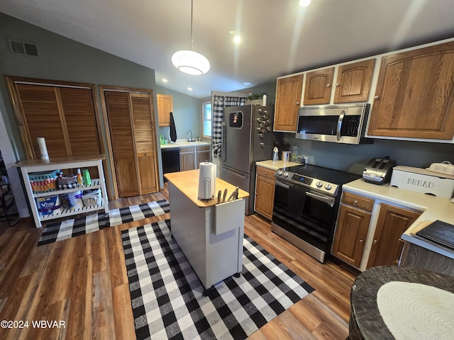 kitchen featuring dark hardwood / wood-style flooring, hanging light fixtures, vaulted ceiling, and appliances with stainless steel finishes