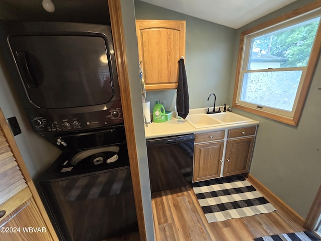 laundry room with stacked washer and dryer, light hardwood / wood-style floors, and sink