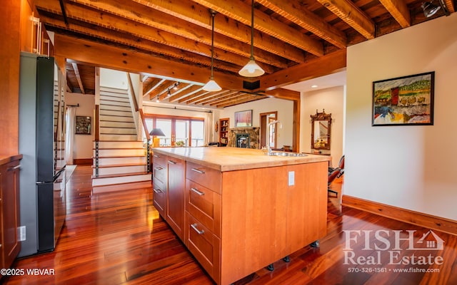 kitchen with stainless steel fridge, sink, beamed ceiling, and hanging light fixtures