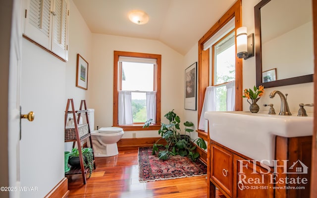 bathroom featuring hardwood / wood-style floors, vanity, toilet, and lofted ceiling