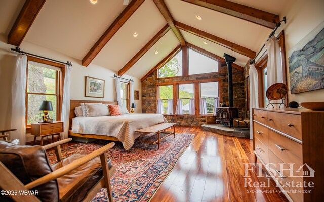 bedroom featuring wood-type flooring, a wood stove, high vaulted ceiling, and multiple windows