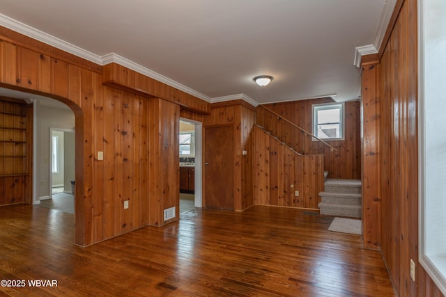 empty room featuring ornamental molding, dark hardwood / wood-style floors, and wood walls