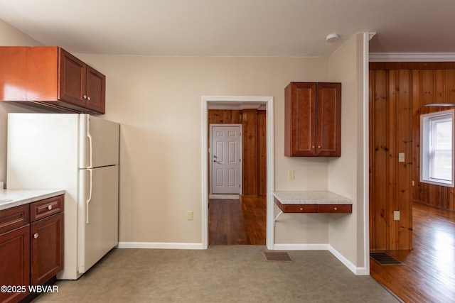 kitchen featuring white refrigerator, wooden walls, and light hardwood / wood-style flooring