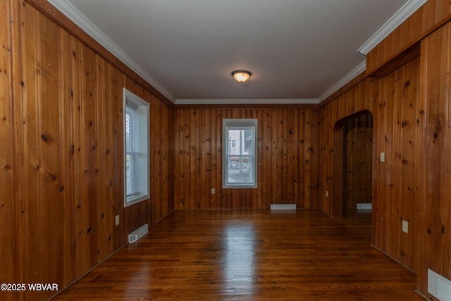 spare room with dark hardwood / wood-style flooring, crown molding, and wood walls