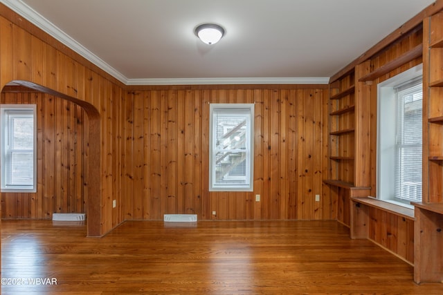 unfurnished room with hardwood / wood-style flooring, ornamental molding, and wooden walls