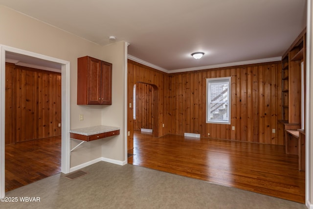 unfurnished room with crown molding, wooden walls, and dark hardwood / wood-style floors