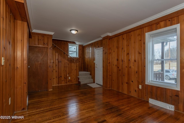 empty room with crown molding, wooden walls, and dark hardwood / wood-style flooring