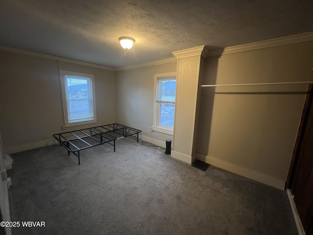 unfurnished bedroom featuring a textured ceiling, dark carpet, and ornamental molding