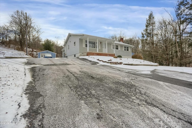 view of front facade featuring covered porch, a garage, and an outdoor structure