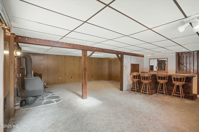 basement with bar, wooden walls, and a drop ceiling