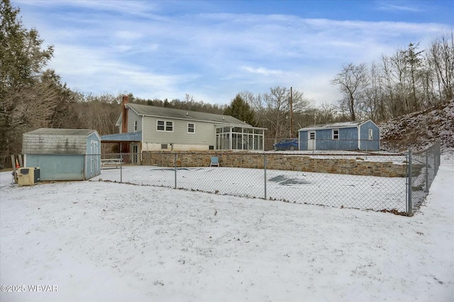 snow covered rear of property featuring a storage unit