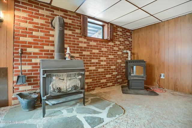 details with a wood stove, a drop ceiling, and wood walls