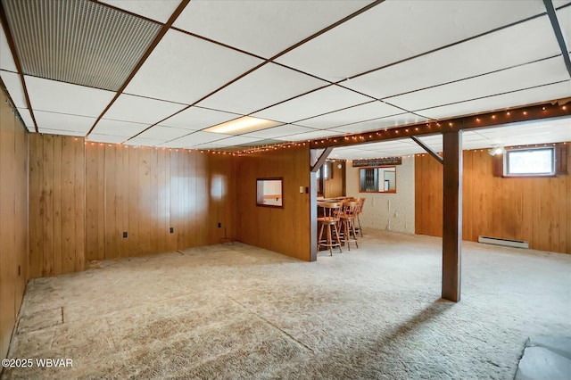 basement with bar area, light carpet, and a baseboard radiator