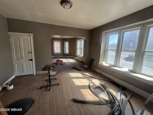 interior space featuring hardwood / wood-style floors, visible vents, baseboards, and arched walkways