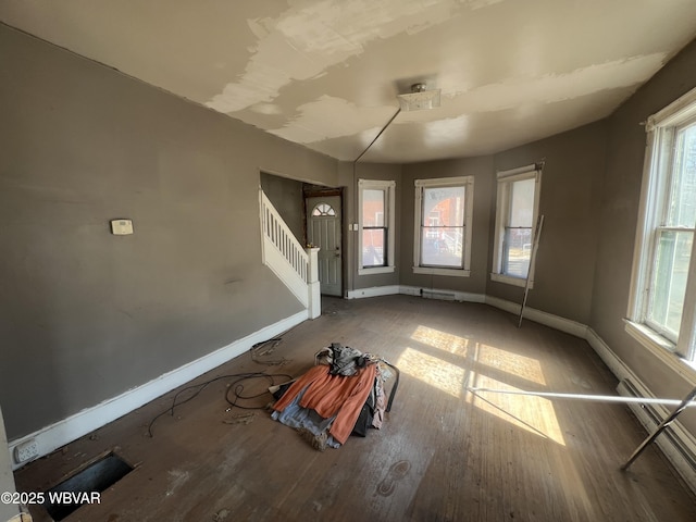 unfurnished living room featuring stairs, wood finished floors, and baseboards