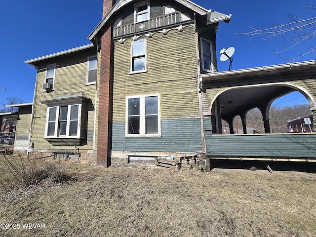 view of side of home with cooling unit and a chimney