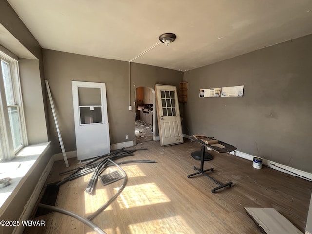 interior space with wood finished floors, arched walkways, and baseboards