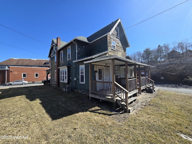 view of front of home with a front lawn, covered porch, and a chimney