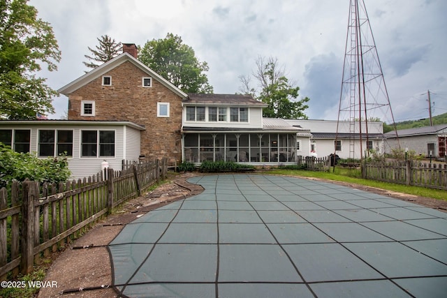 320 Carpenters Ln, Pennsdale, PA 17756 - rear view of property featuring a sunroom, a chimney, a fenced backyard, stone siding, and a patio area
