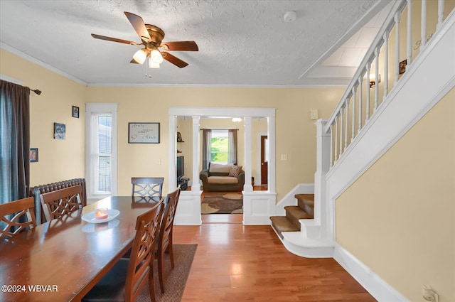 dining room with ceiling fan, wood-type flooring, a textured ceiling, and ornamental molding