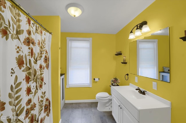 bathroom with hardwood / wood-style floors, vanity, a healthy amount of sunlight, and toilet