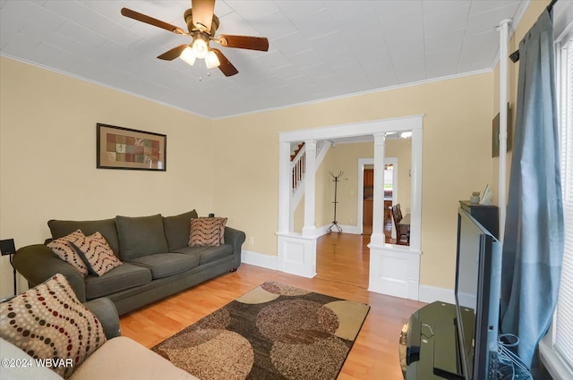 living room with wood-type flooring, decorative columns, ceiling fan, and crown molding