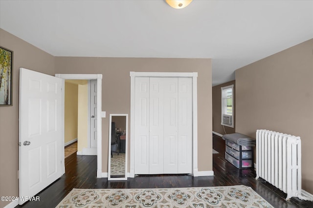 bedroom with a closet, radiator, and dark wood-type flooring