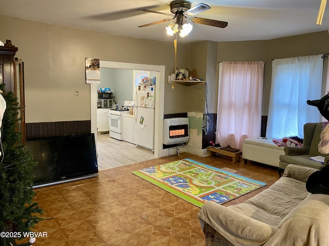 living room featuring ceiling fan, light parquet flooring, and heating unit