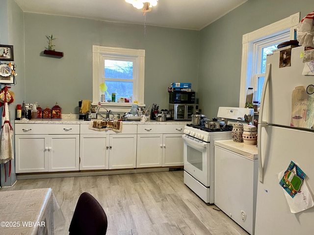 kitchen with light wood-type flooring, sink, white appliances, and white cabinetry