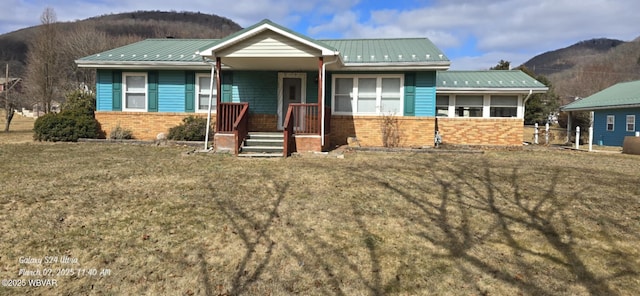 view of front of property with metal roof, brick siding, covered porch, and a mountain view