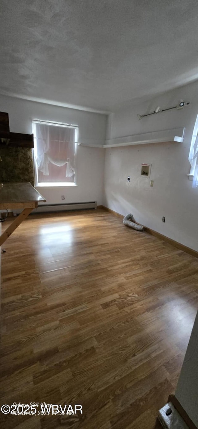 interior space featuring a textured ceiling, wood finished floors, a wealth of natural light, and a baseboard radiator