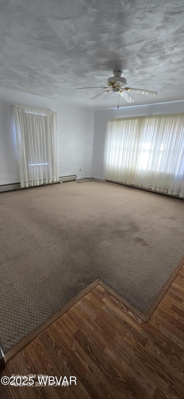 carpeted empty room featuring wood finished floors and a ceiling fan