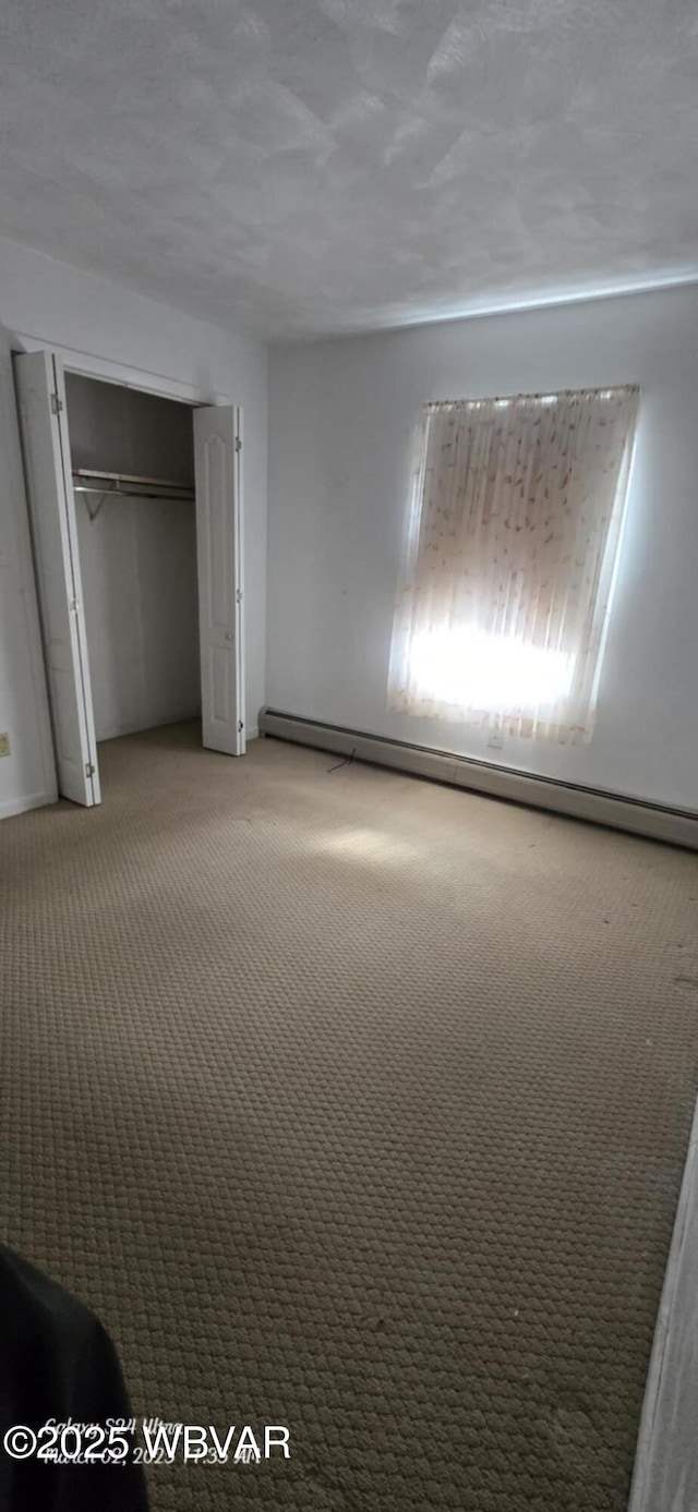 unfurnished bedroom with light carpet, baseboard heating, and a closet