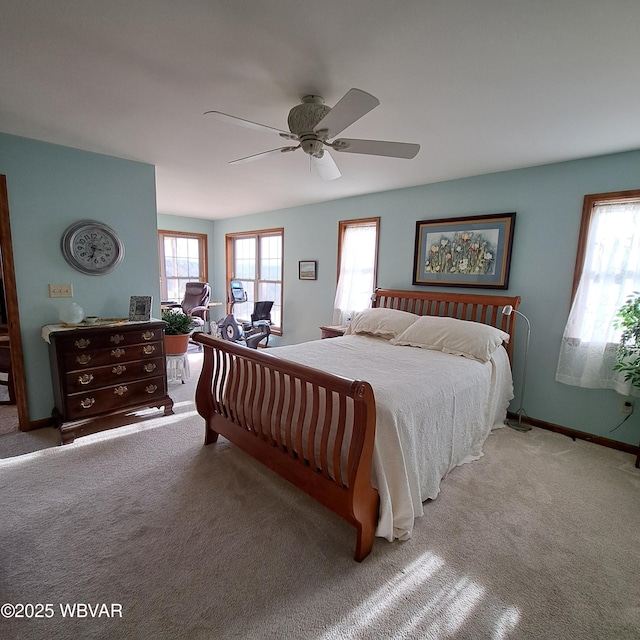 bedroom featuring baseboards, multiple windows, light colored carpet, and a ceiling fan