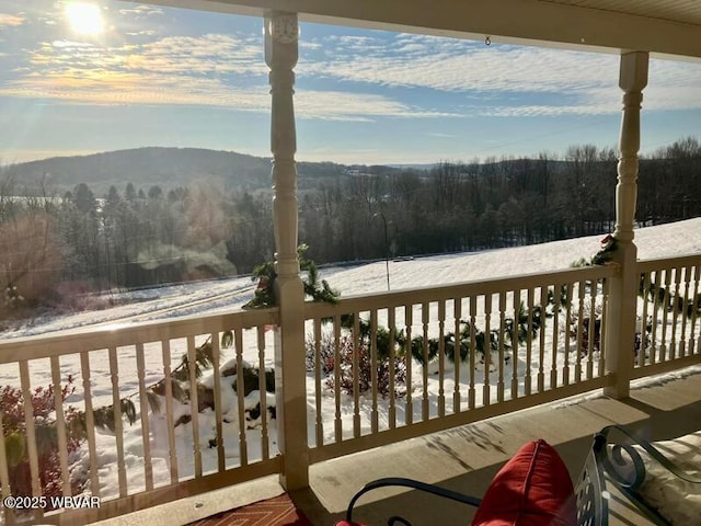 snow covered deck with a wooded view