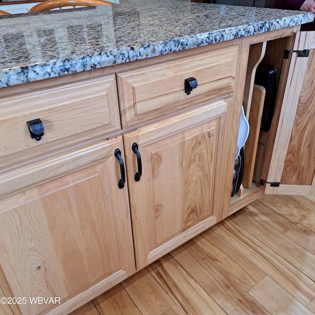 details featuring light brown cabinetry, light wood-style floors, and light stone counters