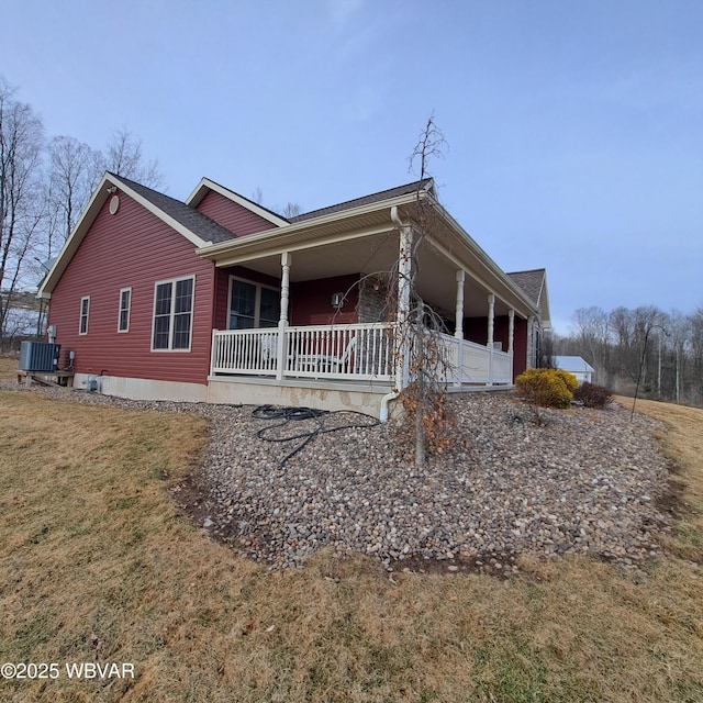 view of side of home featuring cooling unit, a porch, and a yard