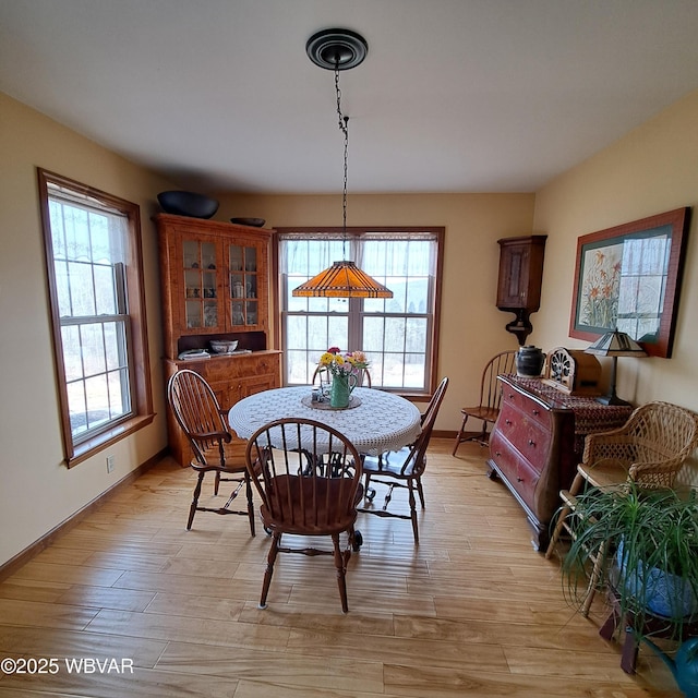 dining area featuring a healthy amount of sunlight, light wood-type flooring, and baseboards