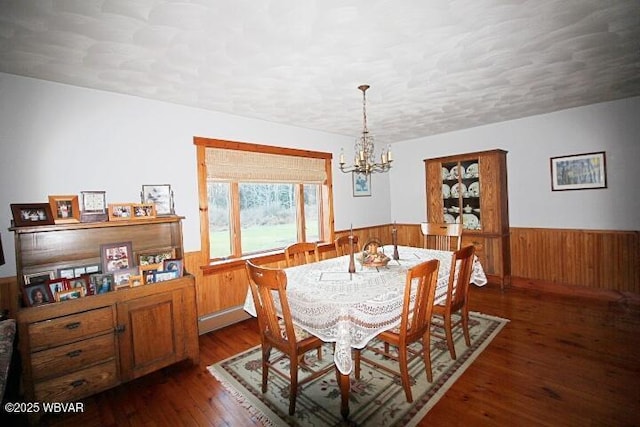 dining area featuring a textured ceiling, wooden walls, dark hardwood / wood-style floors, and a chandelier