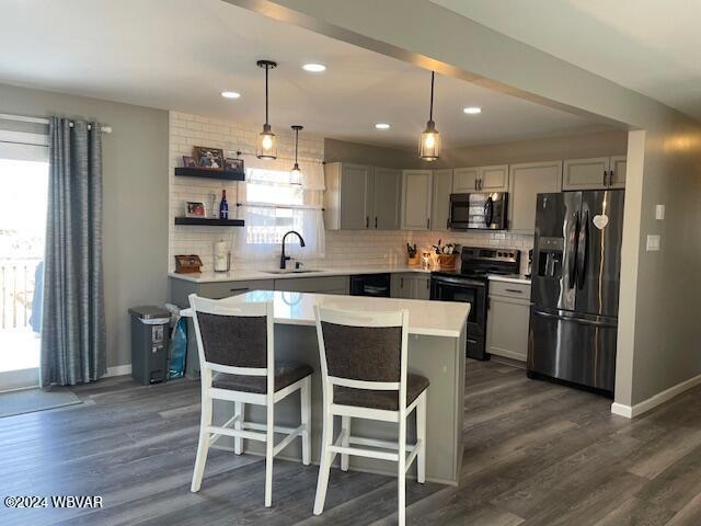 kitchen with gray cabinetry, stainless steel appliances, dark wood-type flooring, pendant lighting, and a center island