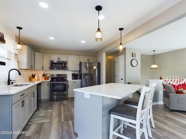 kitchen with pendant lighting, stainless steel appliances, gray cabinets, and hardwood / wood-style floors