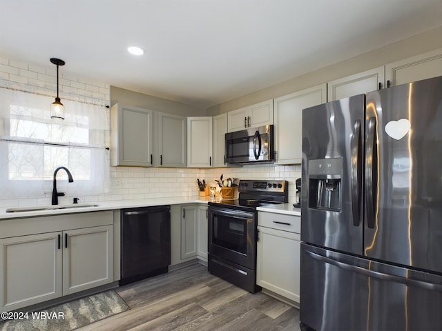 kitchen with appliances with stainless steel finishes, dark hardwood / wood-style flooring, backsplash, sink, and hanging light fixtures