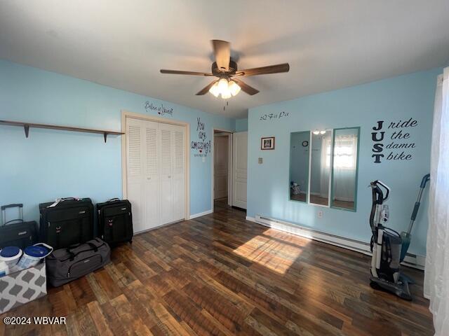 interior space with ceiling fan, dark wood-type flooring, and a baseboard heating unit