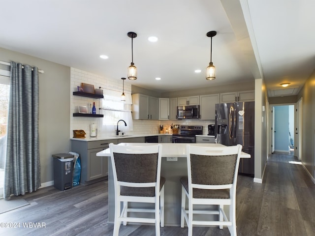 kitchen with a kitchen island, sink, appliances with stainless steel finishes, and dark wood-type flooring