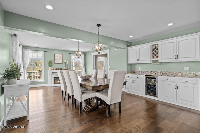 dining room with beverage cooler, dark wood-style floors, bar area, a chandelier, and recessed lighting