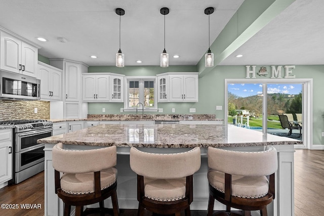 kitchen with stainless steel appliances, a sink, a kitchen island, white cabinets, and recessed lighting