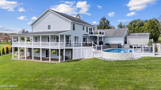 rear view of property with a lawn, an outdoor pool, a deck, and a hot tub