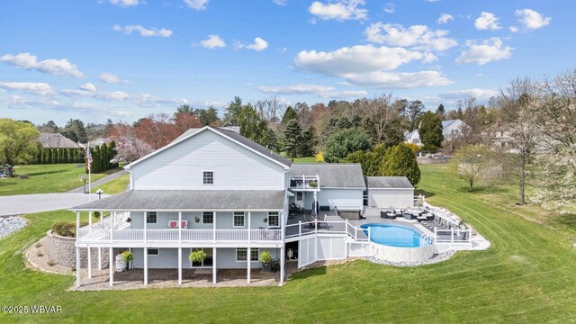 rear view of property with a lawn, an outdoor pool, and a deck