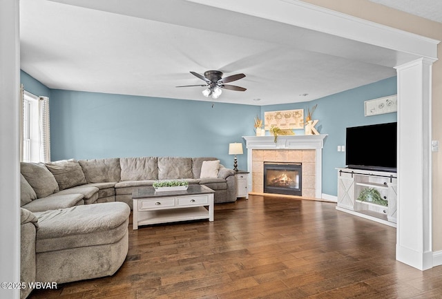living area with a tile fireplace, wood finished floors, and ceiling fan